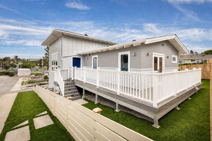 Rear exterior of 501 Grand with wraparound deck, white railing and landscaped yard