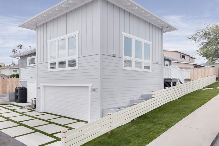 Exterior of 501 Grand showing board-and-batten siding, garage and paver hardscape