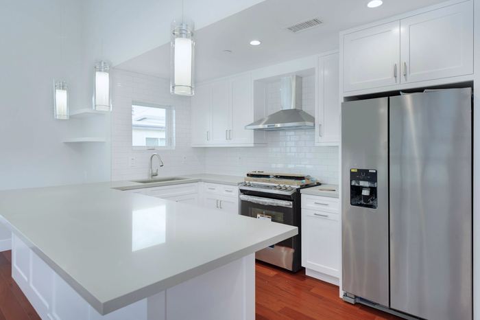 Kitchen with quartz island, gas range and stainless refrigerator