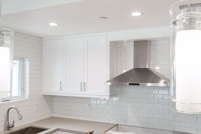 Stainless steel range hood above subway tile backsplash