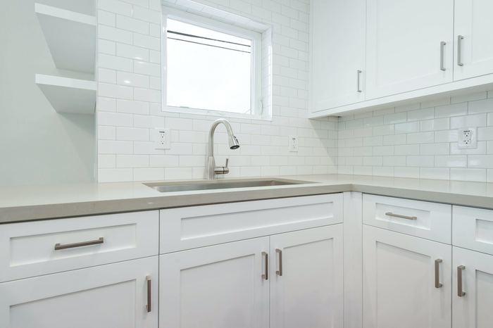 Kitchen sink run with white shaker cabinetry and open shelving