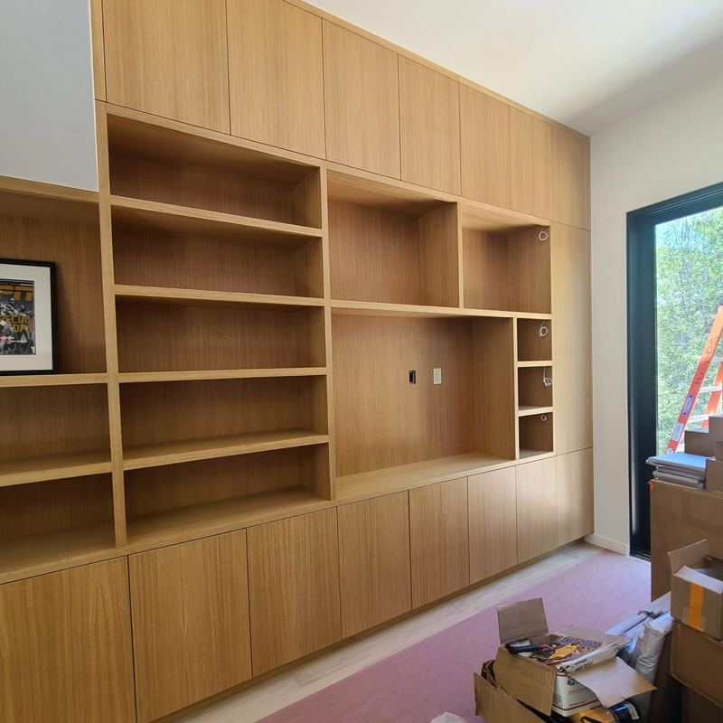 Study wall of white oak built-in shelving and cabinets with a recessed media niche