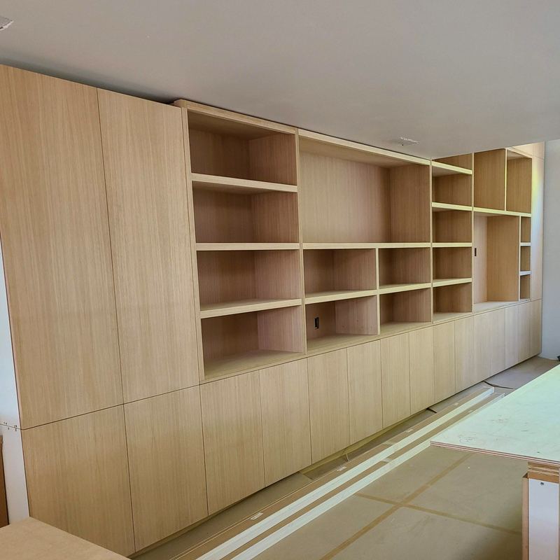 Long white oak casework wall during installation with floor protection still in place