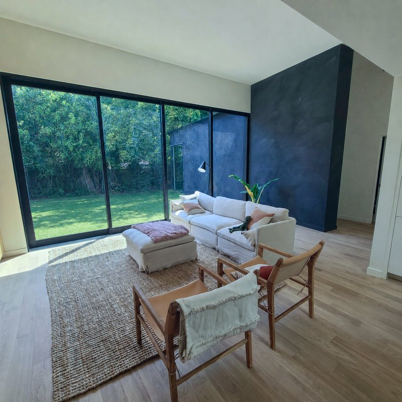 Living room with floor to ceiling black framed sliding glass doors opening to the garden and a deep navy plaster wall